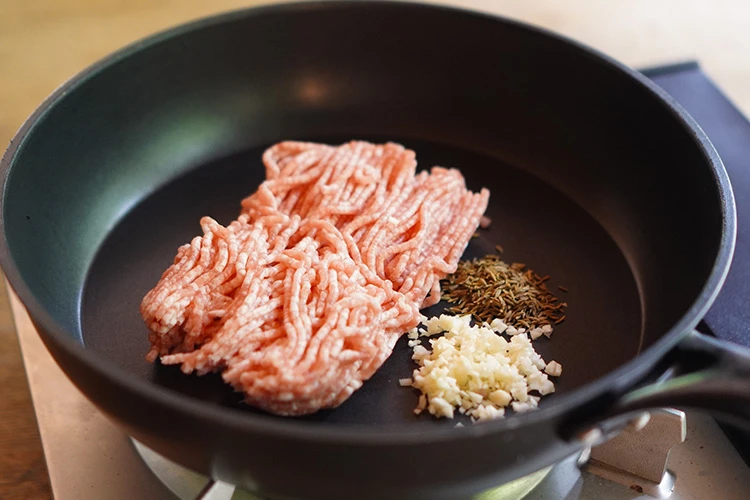 フライパンに豚ひき肉、クミンシード、にんにくを入れる